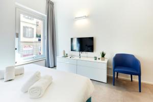 1 dormitorio blanco con TV y silla azul en Suite Meravigli - Incredibile posizione DUOMO e CASTELLO, en Milán