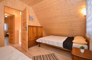 a bedroom with a bed in a wooden cabin at Domki SUNSET Bałtycka in Dąbki