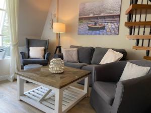 ein Wohnzimmer mit einem Sofa, 2 Stühlen und einem Tisch in der Unterkunft Strandappartment Meerkieker in Travemünde