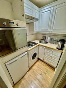 a kitchen with white cabinets and a stove and a dishwasher at Victoria - 1 bedroom appartment 4 people in London