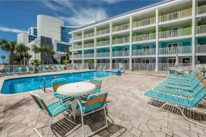 a pool with chairs and a table in front of a hotel at Pelican Point on Clearwater Beach in Clearwater Beach