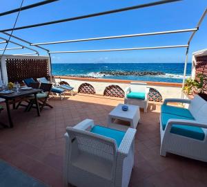 a patio with chairs and tables and the ocean at Raffaela's House - (San Montano) in Massa Lubrense