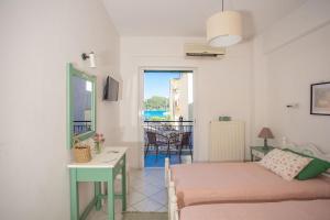 a bedroom with a bed and a table and a balcony at A2- Alexandri Apartment in Nydri
