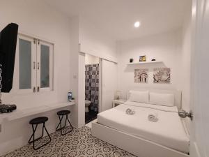 a white bedroom with a bed and a bathroom at Chino Town at Yaowarat Phuket - SHA Plus in Phuket Town