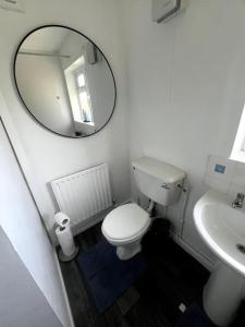 a bathroom with a white toilet and a mirror at Serene Escape in Monmore Green