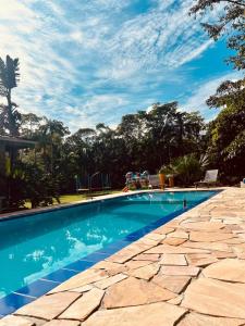 uma piscina com água azul e árvores ao fundo em Sitio Bonanza em Guaratuba