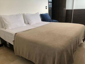 ein großes Bett mit weißer Bettwäsche und Kissen in der Unterkunft 2004 El Poblado cute and cozy apartment in Medellín