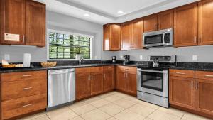 a kitchen with wooden cabinets and stainless steel appliances at Deluxe Townhome - 5 min to Disney World in Orlando