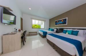 a hotel room with two beds and a desk at Varanasi Hotel Boutique Aeropuerto in Cartagena de Indias