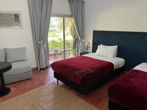 una camera con letto, divano e finestra di Hotel L'Oliveraie Jnane Zitoune a Marrakech