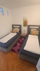 Duas camas individuais num quarto com um tapete em Ferhadija Apartment em Sarajevo