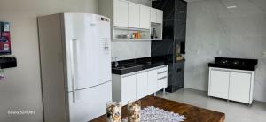  La cuisine est équipée de placards blancs et d'un réfrigérateur. dans l'établissement Casa Temporada Sereia do Mar, à São Mateus