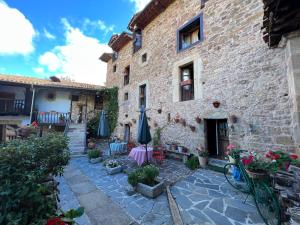 Perrozo的住宿－Posada la Trebede，石头建筑,设有配有桌子和遮阳伞的庭院