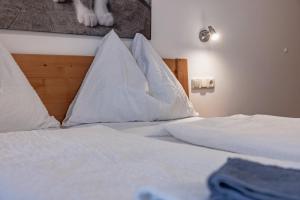 Una cama con sábanas blancas y almohadas. en Bauernhof Pension Hofmayer, en Sankt Kanzian