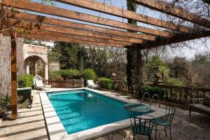 einen Pool in einem Hof mit einer hölzernen Pergola in der Unterkunft Una casa y jardin excepcionales in Piera