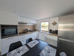 a kitchen with a table and chairs and a refrigerator at 500 m de la plage - Terrasse - 3 chambres in Piriac-sur-Mer
