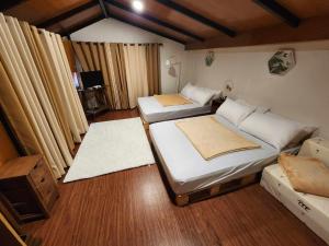 two beds in a room with wooden floors and curtains at Cozy quiet 1BR loft type cabin with own minipool in Rosario