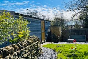 a blue shed with a yellow door in a garden at Shepherds Hut, West Ayton, Scarborough in Scarborough