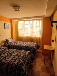 普諾的住宿－Hostal Vista al Lago Titicaca Puno，酒店客房设有两张床和窗户。