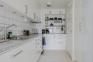 una cucina bianca con armadi bianchi e lavandino di Cozy townhouse 7 beds in Stockholm County a Kungsängen