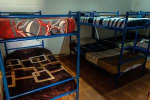 een kamer met 3 stapelbedden en een bed bij Acusi Hostel Camping in Humahuaca