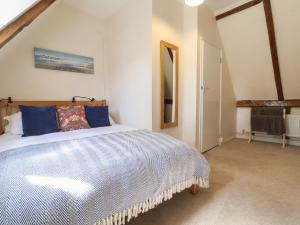 ein Schlafzimmer mit einem großen Bett mit blauen Kissen in der Unterkunft 2 The Almshouses in Saxmundham