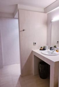 La salle de bains blanche est pourvue d'un lavabo et d'une douche. dans l'établissement Seafront Family Apartment #A, à Argos