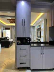 a kitchen with a white cabinet with a microwave at CNJ’s Tranquil Haven in Kampala