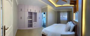 a bedroom with a white bed and white cabinets at CNJ’s Tranquil Haven in Kampala