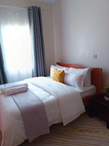 Kai Suites Kitale في كيتالي: غرفة نوم مع سرير أبيض كبير مع نافذة