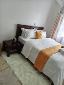 Kai Suites Kitale في كيتالي: غرفة نوم بسريرين وطاولة جانبية