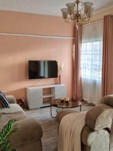 a living room with two couches and a tv at Kai Suites Kitale in Kitale
