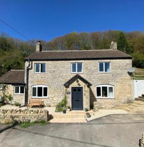 a large stone house with a black door at Springbank Cottage in Stroud