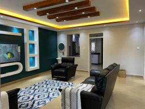 a living room with a bed and two chairs at CNJ’s Tranquil Haven in Kampala