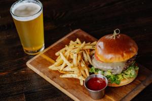 a plate with a burger and french fries and a glass of beer at Snow King Resort Luxury Condominiums in Jackson