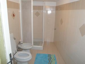 uma casa de banho com um WC, um chuveiro e um tapete. em appartamento x 6 persone em Monasterolo del Castello
