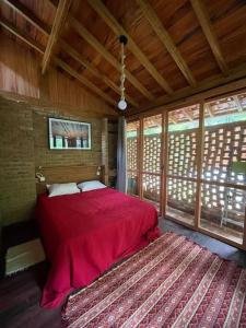 sypialnia z czerwonym łóżkiem w pokoju z oknami w obiekcie Chalé aconchegante cercado pelo verde w mieście Nova Friburgo