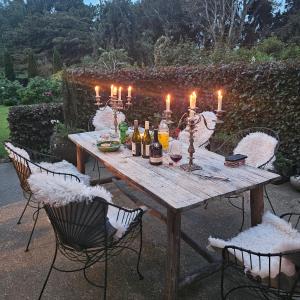 una mesa de madera con velas, botellas y sillas en Whiteacres en Invercargill
