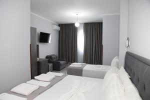 Dormitorio blanco con cama, sofá y silla en DEAL Castle View Rooms en Krujë