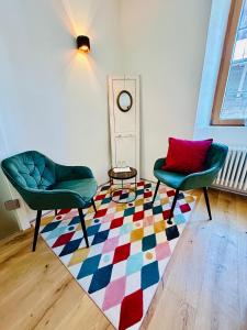 a room with two chairs and a colorful rug at Hotel Des Alpes in Inden