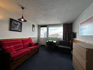 ein Wohnzimmer mit einem roten Sofa und einem Tisch in der Unterkunft Studio Les Menuires, 1 pièce, 2 personnes - FR-1-452-264 in Les Menuires