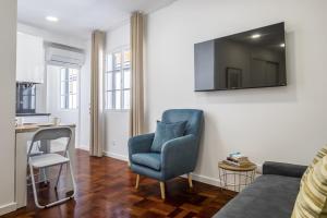 a living room with a blue chair and a television on a wall at Ribeira do Esmeraldo by Homie in Funchal