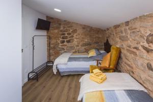 a bedroom with two beds and a stone wall at Casa Lela Dumbria in Dumbría