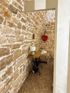 eine Steinmauer mit einem Tisch mit einem Herz an der Wand in der Unterkunft B&B PIETRA VIVA in Sannicandro di Bari