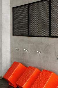 three orange benches against a wall with water faucets at COOLFREEDIVING Hostel in Green Island