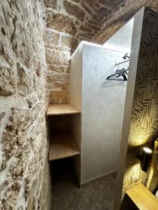 Zimmer mit einer Steinmauer und einem Holzregal in der Unterkunft B&B PIETRA VIVA in Sannicandro di Bari