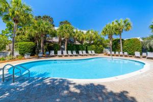 a swimming pool with chairs and palm trees at Cassine Gardens by Panhandle Getaways in Santa Rosa Beach