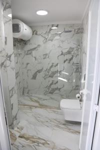 bagno con servizi igienici e parete in marmo. di DEAL Castle View Rooms a Krujë (Kruja)