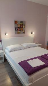 a large white bed with a purple blanket on it at Apartments Gojka Miocevic in Biograd na Moru