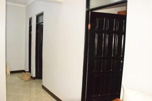 a hallway with a black door and a white wall at Two Bedrooms Apartment Moshi in Bunju